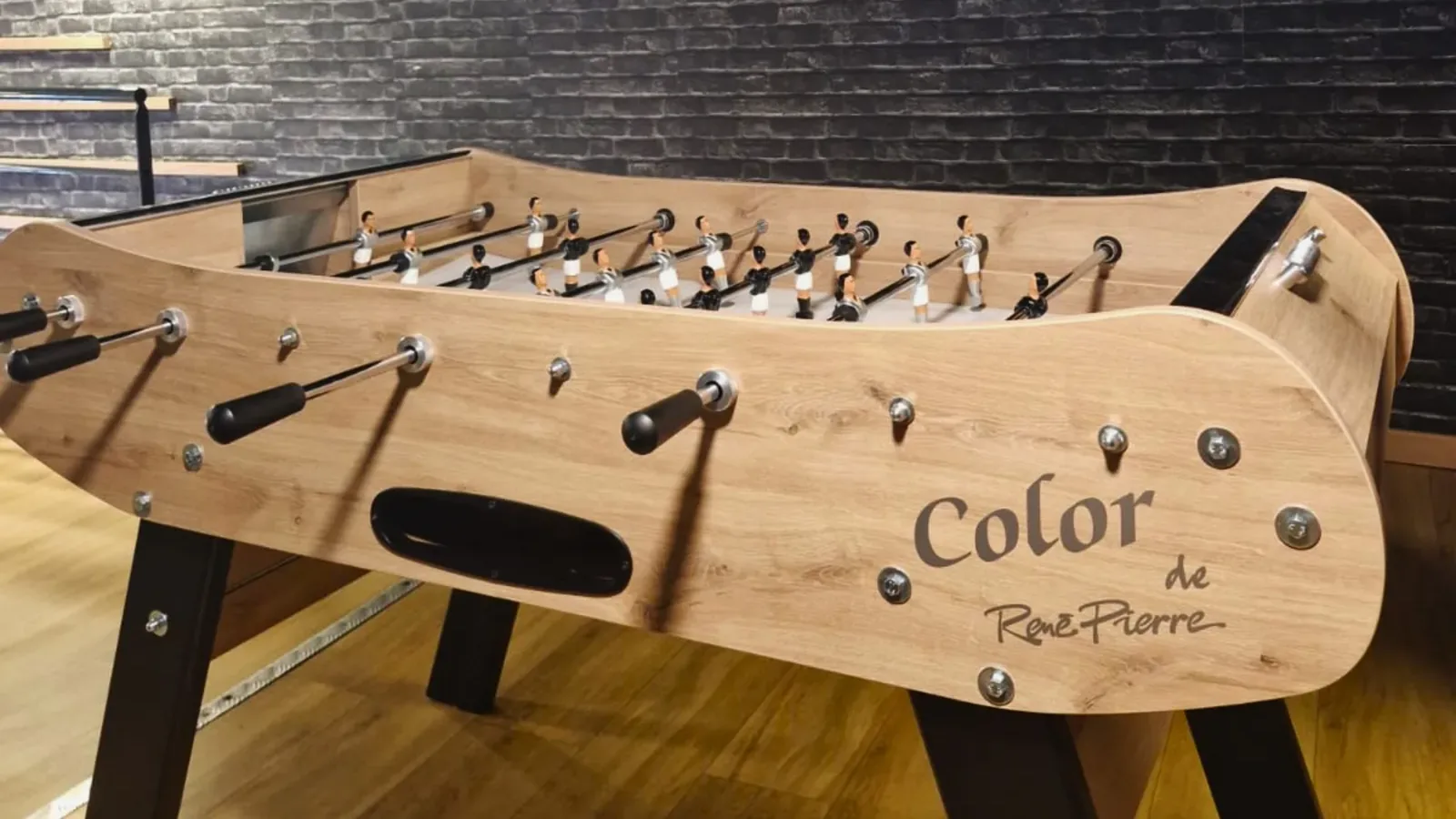 Baby-foot en bois installé dans une salle aux murs de briques